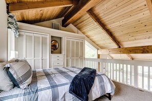 Un dormitorio con cama, contraventanas blancas, ventilador de techo y vistas al exterior.
