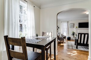 Un comedor con mesa y sillas de madera, una chimenea y una sala de estar al fondo.