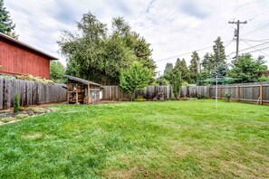 A backyard with a wooden fence, a red barn, and a garden area. - Pet-Friendly Cottage in Walkable Whiteaker w/ (Eugene)