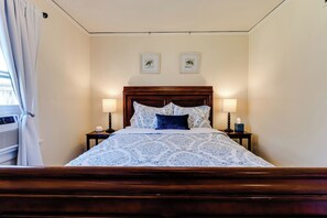 A neatly made bed with a patterned bedspread, two bedside lamps, and a wooden headboard. - Pet-Friendly Cottage in Walkable Whiteaker w/ (Eugene)