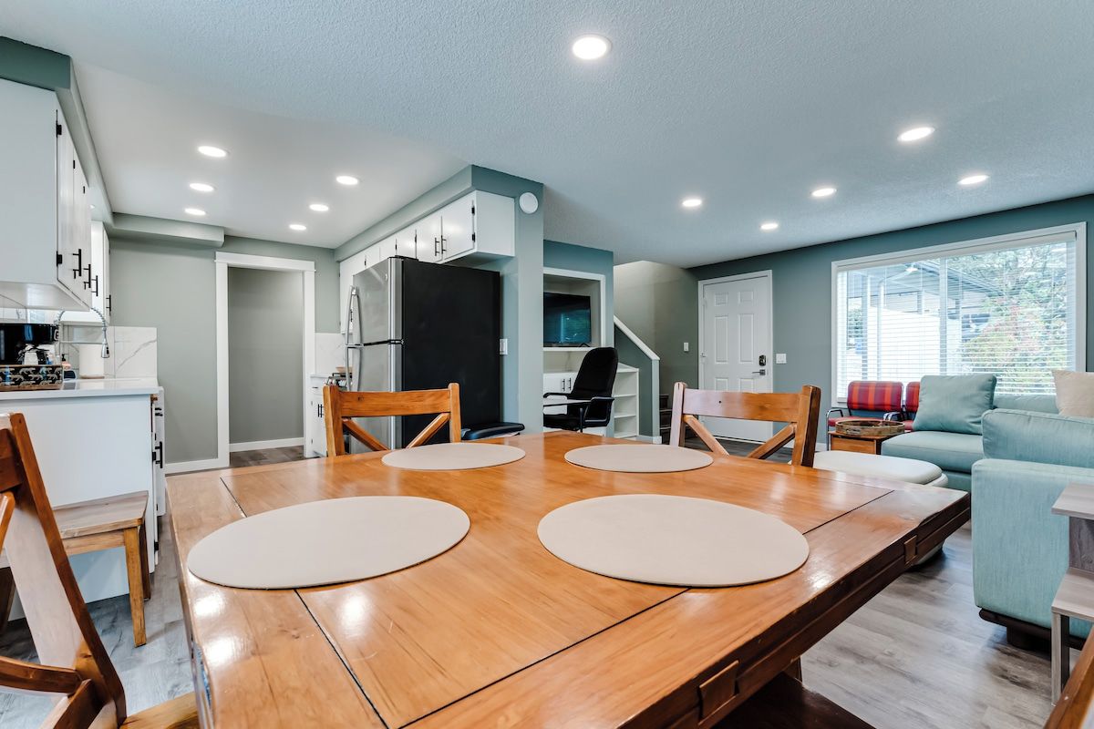 A modern kitchen with a dining area, wooden table, and chairs.
