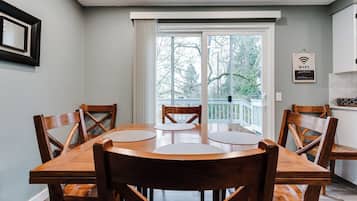 A dining area with a wooden table and chairs, a large window with a view of trees, and a WiFi sign on the wall.