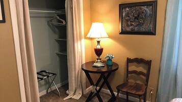 Ett hotellrum med en garderob, ett bord med en lampa, en stol och en tavla på väggen.