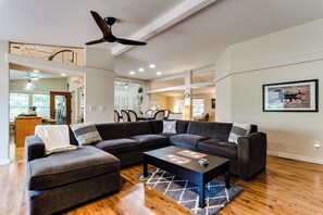 A spacious living room with a sectional sofa, a coffee table, and a ceiling fan. - Secluded Garden Retreat w/ Game Room & BBQ Patio (Eugene)
