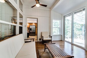 A spacious room with a wooden bench, a white sofa, a chair, and a ceiling fan. - Secluded Garden Retreat w/ Game Room & BBQ Patio (Eugene)