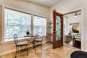 A dining area with a table and chairs, a potted plant, and a view through a glass door to a living space. - Secluded Garden Retreat w/ Game Room & BBQ Patio (Eugene)