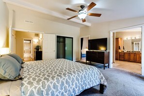 A bedroom with a bed, a ceiling fan, a TV, and a view into the kitchen. - Secluded Garden Retreat w/ Game Room & BBQ Patio (Eugene)