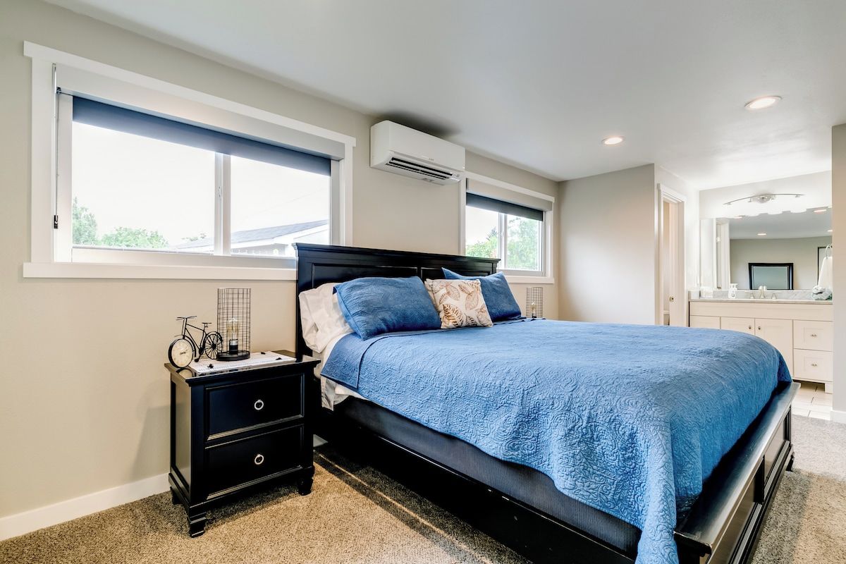Een slaapkamer met een bed, nachtkastje, dressoir en raam.