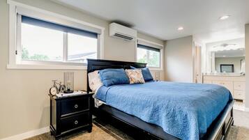 Een slaapkamer met een bed, nachtkastje, dressoir en raam.