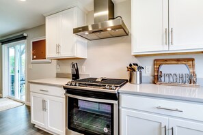 Une cuisine moderne avec des meubles blancs, une hotte en acier inoxydable et un four.