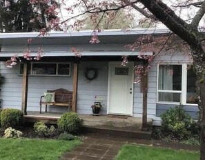 Ein Wohnhaus mit Veranda, einer Bank, einem Kranz und einem Blumentopf.