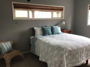 Ein Schlafzimmer mit Bett, Fenster, Nachttisch und Stuhl.