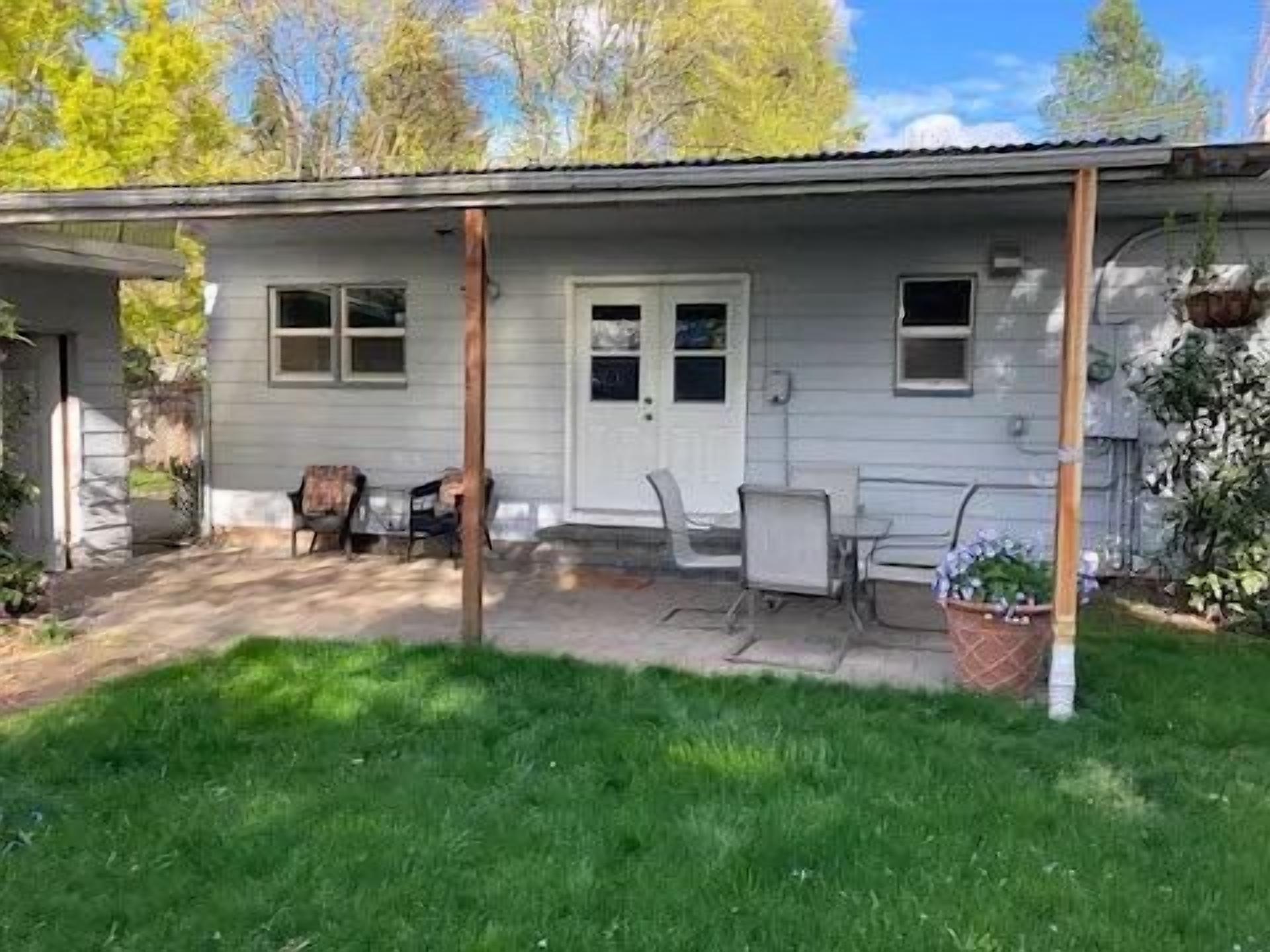 Ein eingeschossiges Haus mit Veranda, einer Tür und einer kleinen angebauten Garage.