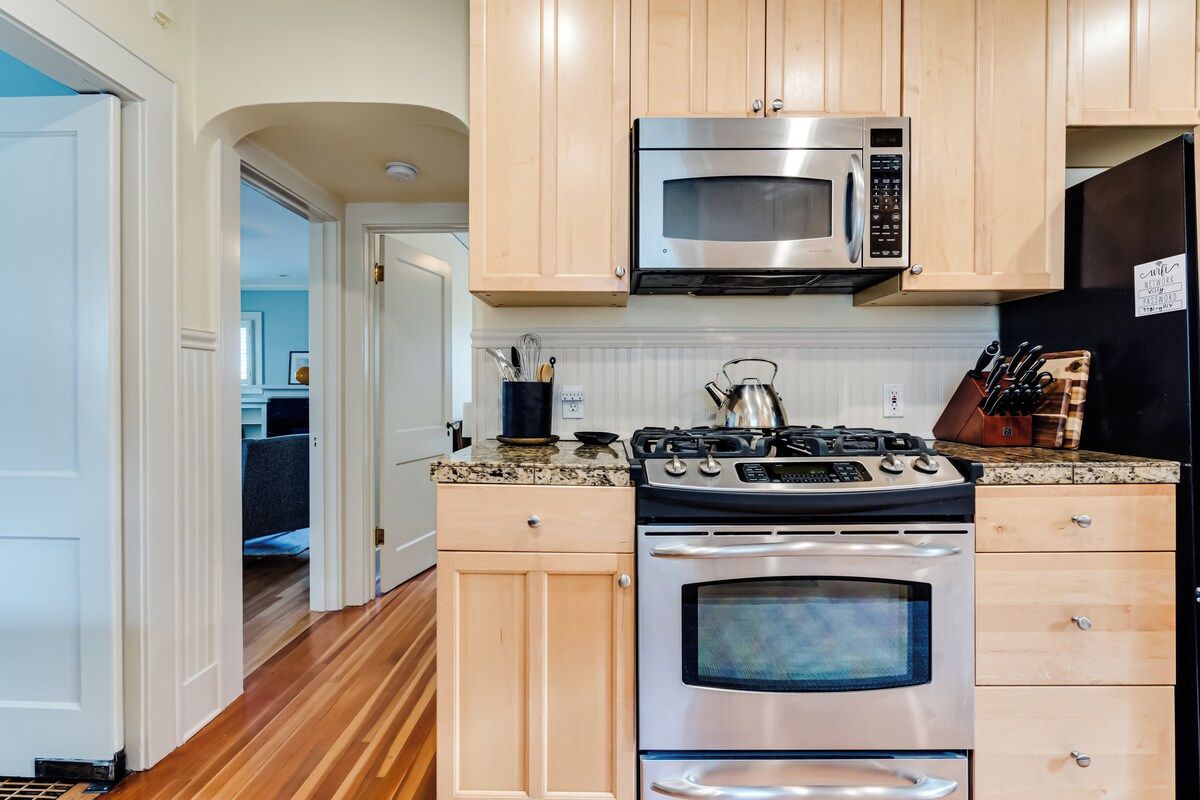 A kitchen with wooden cabinets, a stainless steel stove, a microwave, and a refrigerator.