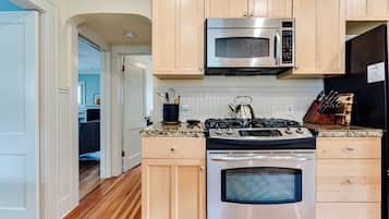 A kitchen with wooden cabinets, a stainless steel stove, a microwave, and a refrigerator.