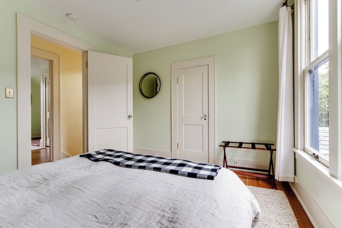 A bedroom with a bed, a wardrobe, a mirror, and a window.