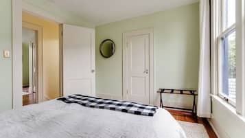A bedroom with a bed, a wardrobe, a mirror, and a window.
