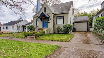 A residential house with a front porch, a garage, and a well-maintained lawn.