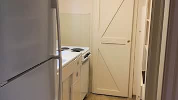 A compact kitchen with a refrigerator, stove, and cabinets.