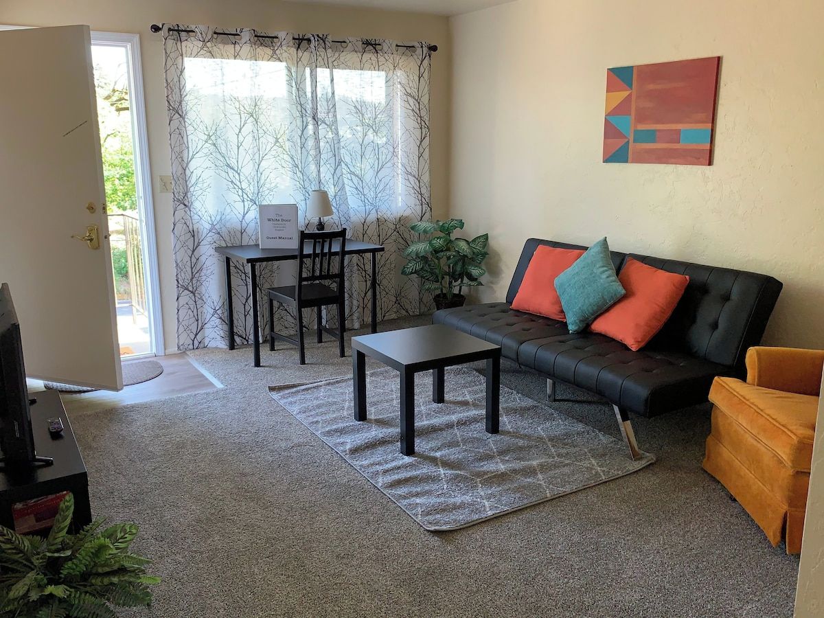A living room with a sofa, a coffee table, a TV, and a dining area with a table and chairs.