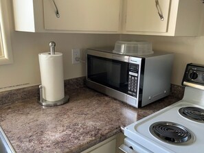 A kitchen with a microwave, a stove, and a paper towel holder. - The White Door: Modern Upstairs in Downtown Eugene (Eugene)