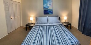 Une chambre d’hôtel avec un lit, deux lampes de chevet, un tableau au mur et une porte à panneaux ajourés.