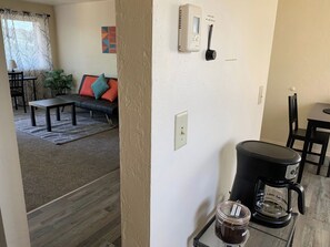 A living area with a sofa, a coffee maker, and a wall-mounted thermostat. - The White Door: Modern Upstairs in Downtown Eugene (Eugene)