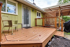 Eine Holzterrasse mit überdachtem Bereich, einer Tür und einem Stuhl.