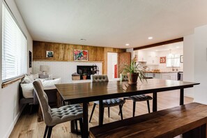 Un espace repas moderne avec une table en bois, des chaises rembourrées et une cheminée.
