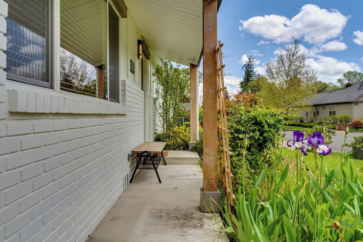 Une maison avec un porche abrité, une table et un jardin fleuri.