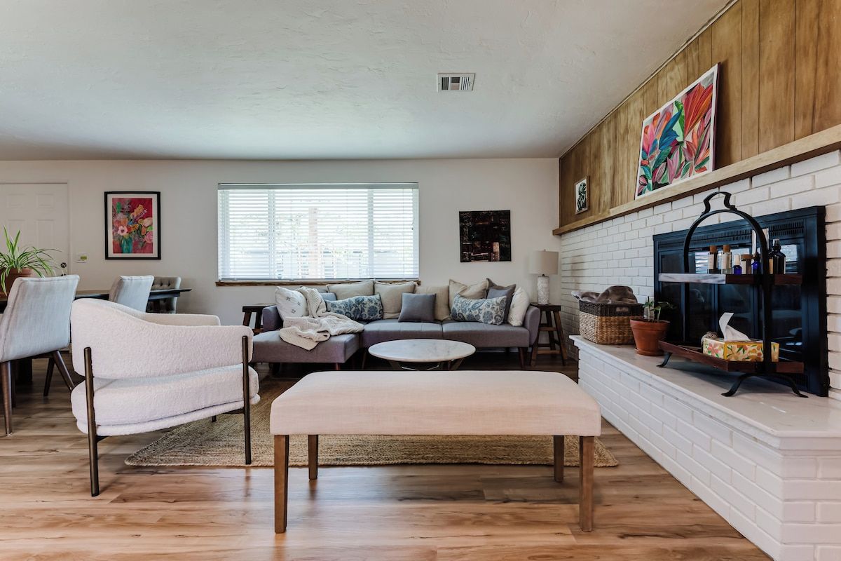 A living room with a fireplace, a sofa set, a coffee table, and a dining area with chairs.
