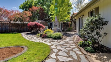A residential property with a stone pathway leading to a covered patio area.