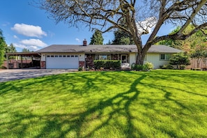 A single-story house with a garage, a covered driveway, and a well-maintained lawn. - Serene Backyard Oasis w/ Free Parking & Modern (Eugene)