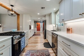 A modern kitchen with white cabinets, stainless steel appliances, and a patterned rug. - Serene Backyard Oasis w/ Free Parking & Modern (Eugene)