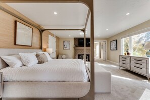 A bedroom with a large bed, a fireplace, and a view of the outdoors. - Luxury Eugene Home w/Gourmet Kitchen & Office (Eugene)