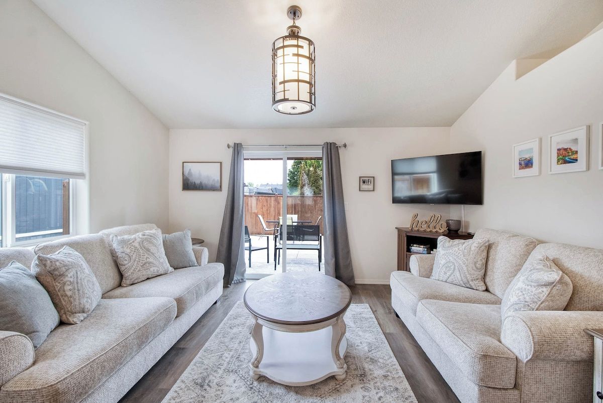 A living room with two sofas, a coffee table, a TV, and a ceiling light fixture.