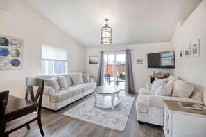 A modern living room with two sofas, a coffee table, a TV, and a dining area with a table and chairs. - Welcome to Eugene - Track Town USA - 3bedroom home (Eugene)