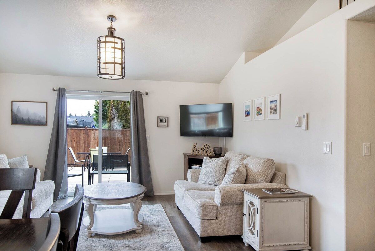 A living room with a sofa, a TV, a dining table, and a chandelier.