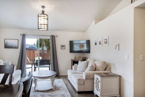 A living room with a sofa, a TV, a dining table, and a chandelier. - Welcome to Eugene - Track Town USA - 3bedroom home (Eugene)