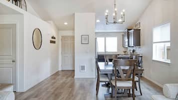 A spacious kitchen with a dining area, wooden flooring, and a chandelier.