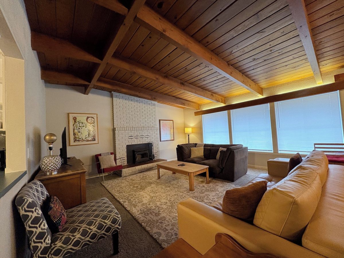 A living room with a fireplace, a sofa, a coffee table, and a patterned rug.