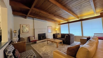 A living room with a fireplace, a sofa, a coffee table, and a patterned rug.