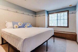 Ein Schlafzimmer mit einem Bett, einem Fenster mit Jalousien und einer Wand mit Landschaftsbild.