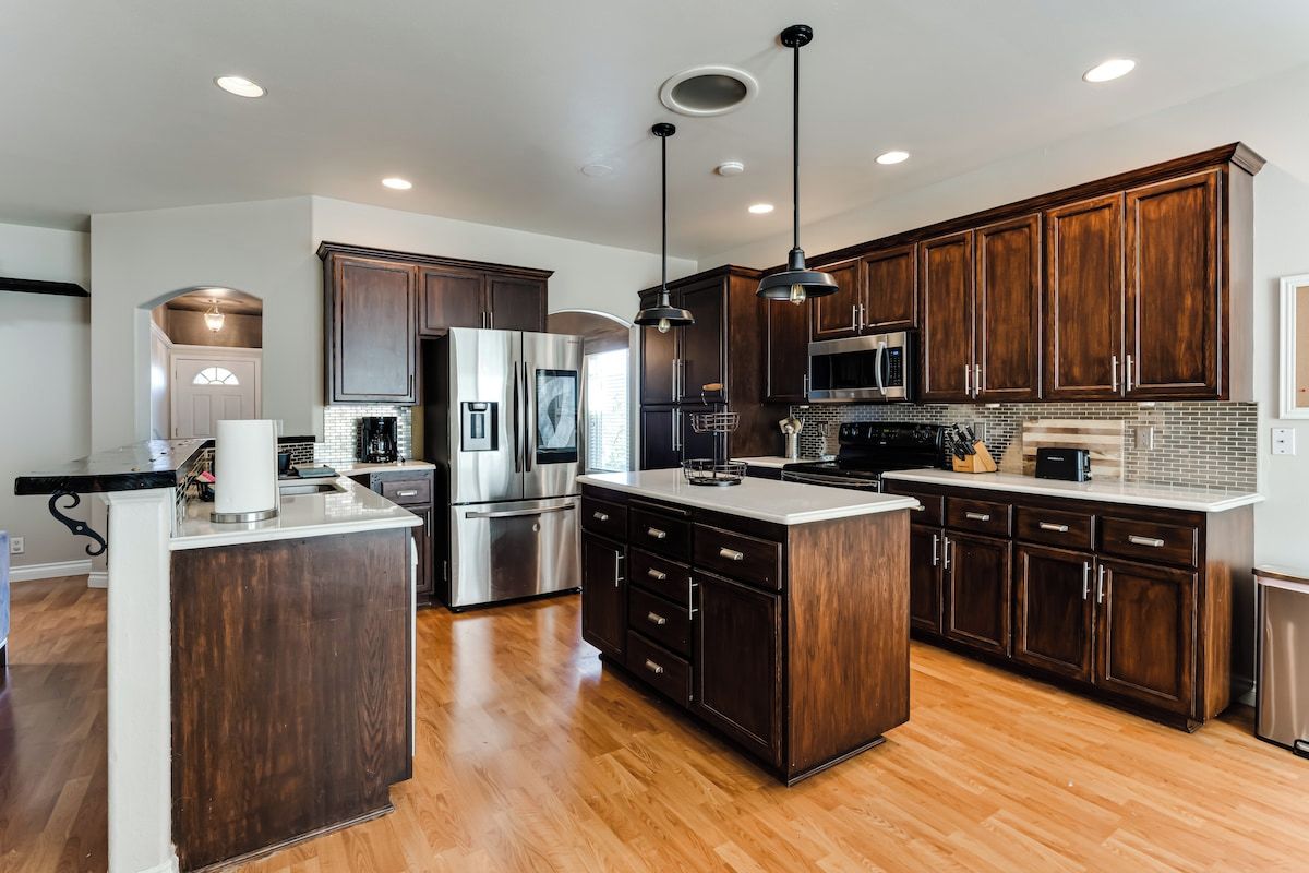 A modern kitchen with dark wood cabinets, stainless steel appliances, and a central island.
