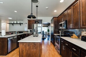 A modern kitchen with dark wood cabinets, stainless steel appliances, and a central island. - Thurston Hills Retreat: Modern Home w/ Scenic (Springfield)