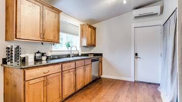 A kitchen with wooden cabinets, a countertop, a dishwasher, and an air conditioning unit.
