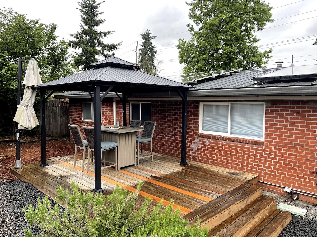 Un patio couvert avec une table et des chaises, une maison en briques et une terrasse en bois.