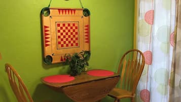 Un comedor con una mesa y sillas de madera, un reloj de pared y un patrón de cuadros en la pared.
