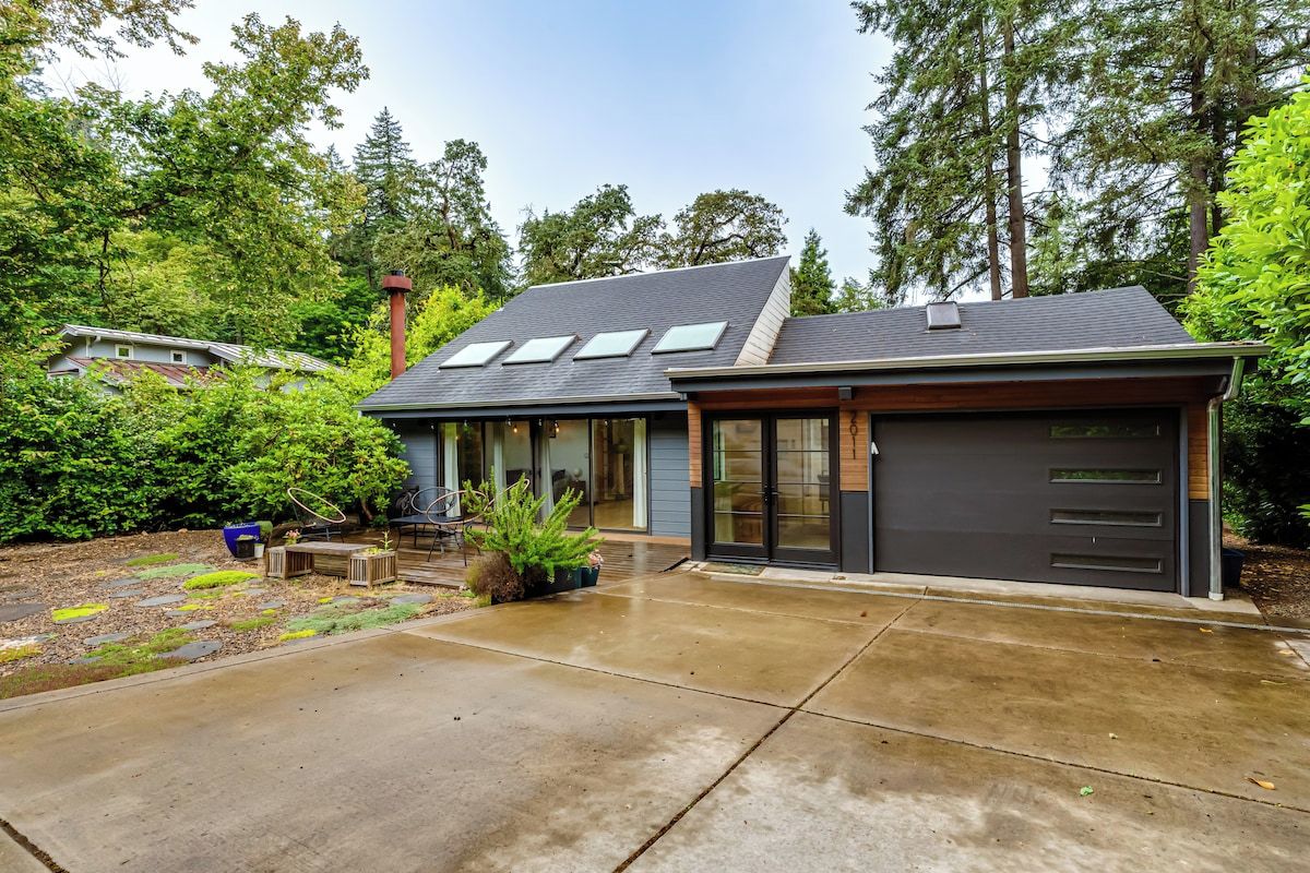 Ein modernes, zweistöckiges Haus mit Garage, überdachter Terrasse und gepflegtem Garten.