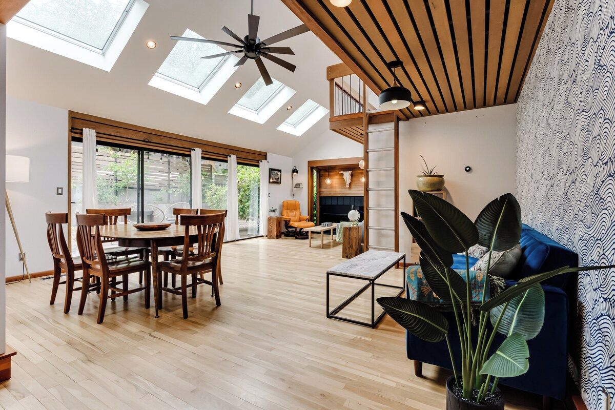 A spacious living area with a dining table, chairs, a blue sofa, and a large plant.